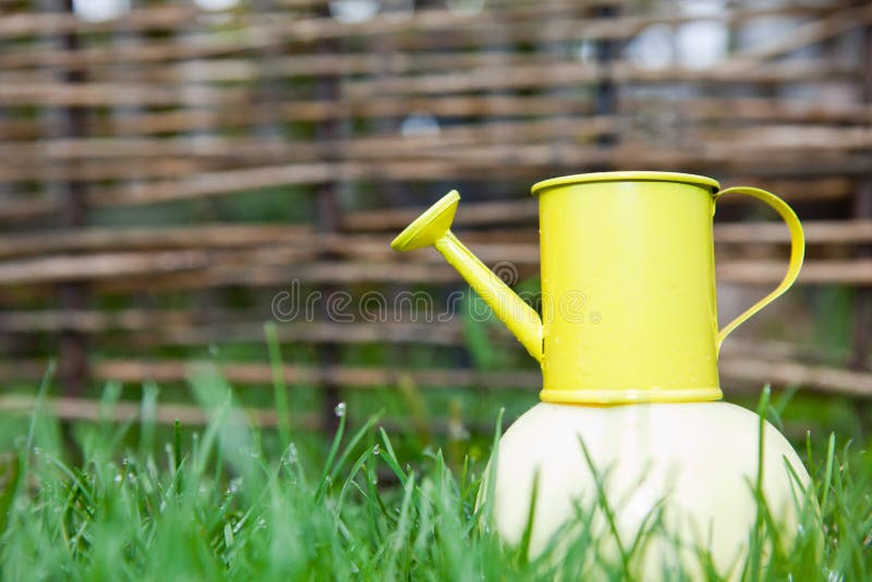 Yellow watering can on an apple on background stock photo Yellow watering can on an apple on background stock photo