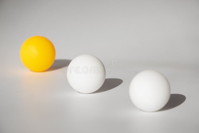 Yellow and white ping pong balls on a white background with hard light and shadows