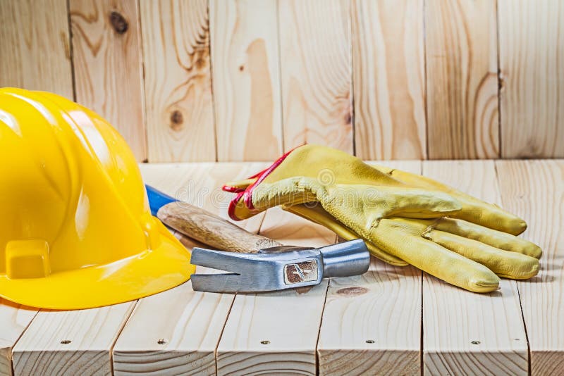 Yellow working gloves claw hammer and helmet on wooden background stock images Yellow working gloves claw hammer and helmet on wooden background stock images