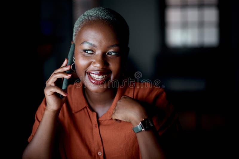 Yes, I got everything done this evening. a young businesswoman talking on a cellphone in an office at night. royalty free stock photo