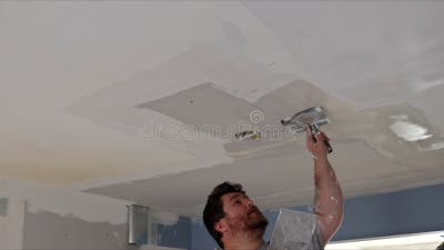 joven hombre utilizando espátula y enlucido de pared con blanco