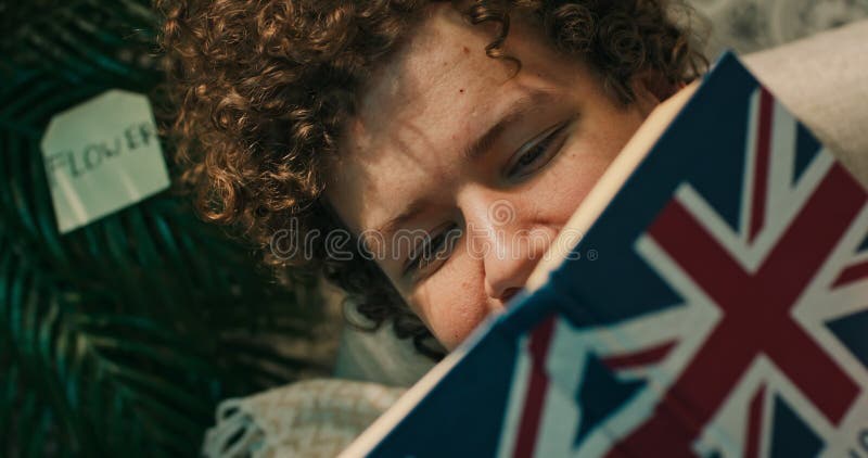 Yeux d'un adolescent lisant un manuel de dictionnaire anglais. jeune garçon étudie couvre son visage avec un livre mystérieux clips vidéos