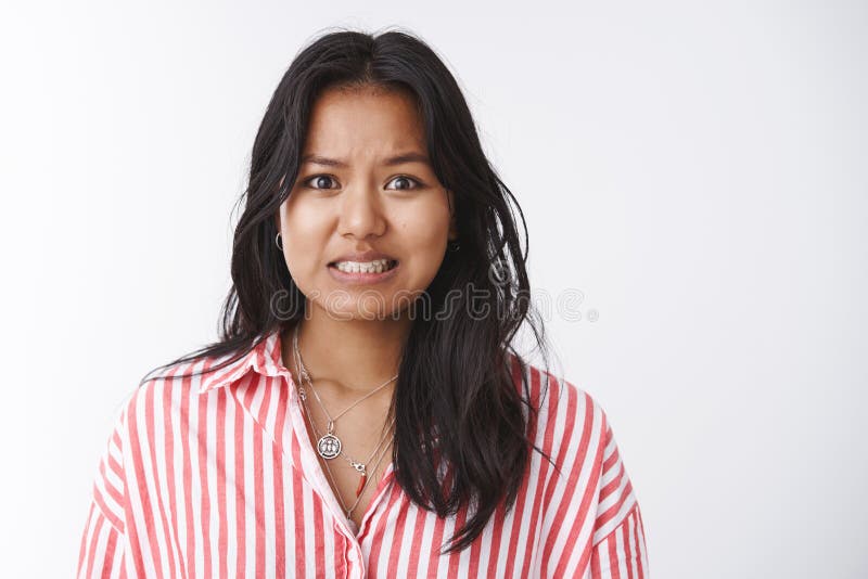 Yikes I am in trouble. Portrait of worried insecure and troubled cute female coworker making huge mess at work clenching teeth awkward and sorry admitting fault saying oops over white background. Yikes I am in trouble. Portrait of worried insecure and troubled cute female coworker making huge mess at work clenching teeth awkward and sorry admitting fault saying oops over white background.