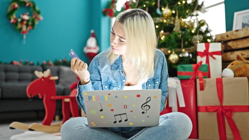 Yngre, vacker historisk kvinna som handlar med en bärbar dator och ett kreditkort som firar jul hemma arkivfoton
