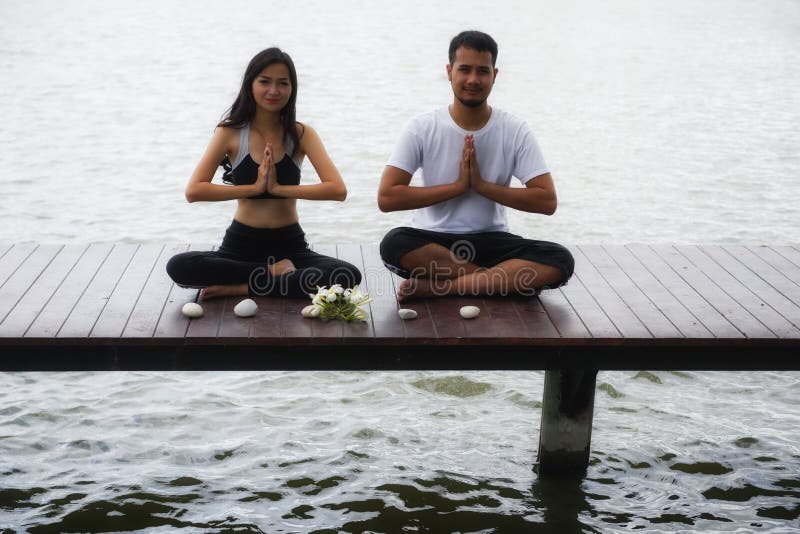 Yoga asiática de la mano de los pares en el lago fotos de archivo libres de regalías Yoga asiática de la mano de los pares en el lago fotos de archivo libres de regalías