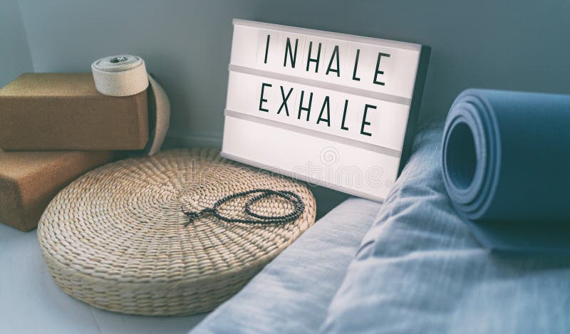 Yoga breathing INHALE EXHALE sign at fitness class on lightbox inspirational message with exercise mat, mala beads. Meditation pillow. Accessories for fit home royalty free stock photo