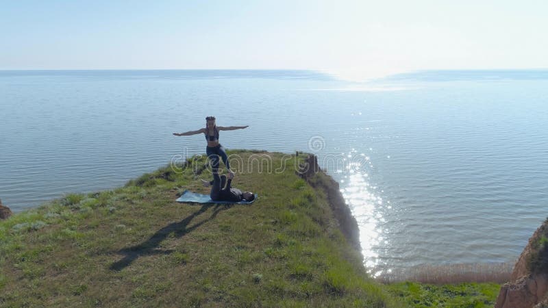 Yoga dans la nature, le mâle fort de yogi et l'acroyoga femelle flexible de pratique sur le rivage en nature près de mer