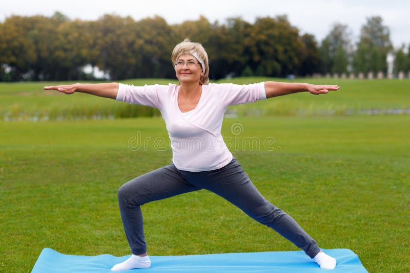 Yoga de pratique de femme mûre en parc photos libres de droits Yoga de pratique de femme mûre en parc photos libres de droits