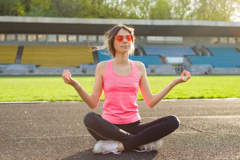 Yoga de pratique de jeune belle adolescente dans le stade photos stock Yoga de pratique de jeune belle adolescente dans le stade photos stock