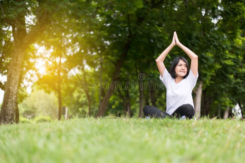 Yoga della donna asiatica al parco di mattina, felice di pratica e sorridere, concetto a pensiero del positivo, a sano ed a stile fotografia stock Yoga della donna asiatica al parco di mattina, felice di pratica e sorridere, concetto a pensiero del positivo, a sano ed a stile fotografia stock