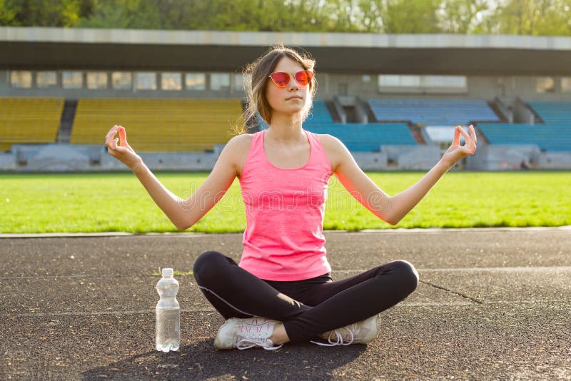 Yoga di pratica del giovane bello adolescente nello stadio fotografia stock Yoga di pratica del giovane bello adolescente nello stadio fotografia stock