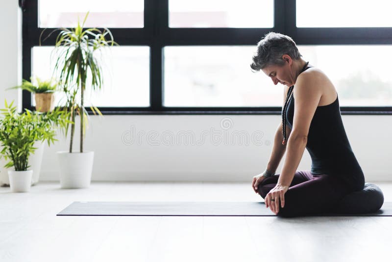 Yoga di pratica della donna caucasica matura sul pavimento del salone immagine stock libera da diritti Yoga di pratica della donna caucasica matura sul pavimento del salone immagine stock libera da diritti