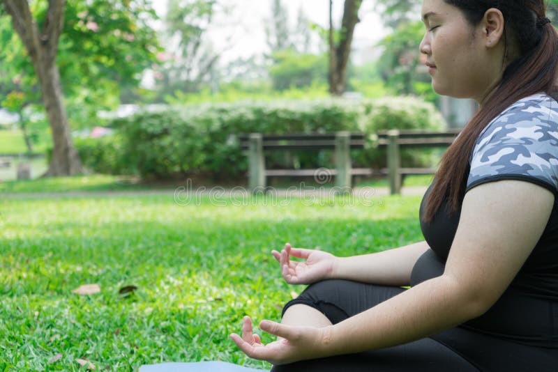 Yoga di pratica e meditazione della donna grassa su erba verde nel parco spazio di concetto e della copia di salute immagini stock Yoga di pratica e meditazione della donna grassa su erba verde nel parco spazio di concetto e della copia di salute immagini stock