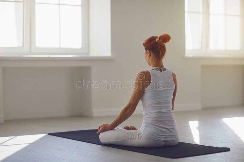 Yoga girl. Backview. Fitness girl is practicing yoga in a lotus position sitting in a studio