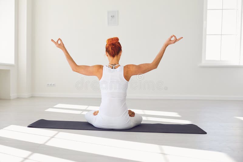 Yoga girl. Backview. Fitness girl is practicing yoga in a lotus position sitting in a studio