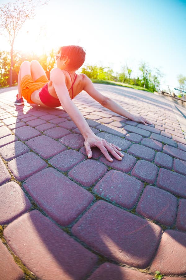 Yoga i gatorna av staden En flicka gör övningar på gryning En kvinna utbildar i parkera Brunetten mediterar i natur Tyst ställe för utbildning i en livlig stad