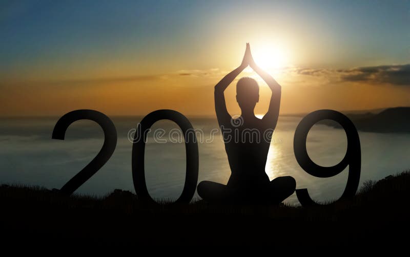 New year and new beginnings concept. Silhouette of person meditating in lotus pose as part of 2019 number on sunrise. New year and new beginnings concept. Silhouette of person meditating in lotus pose as part of 2019 number on sunrise