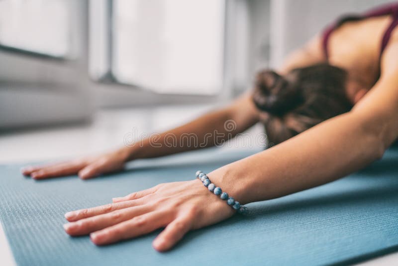 Yoga meditation wellness background - woman doing childs pose stretch on exercise mat - training fitness class at home