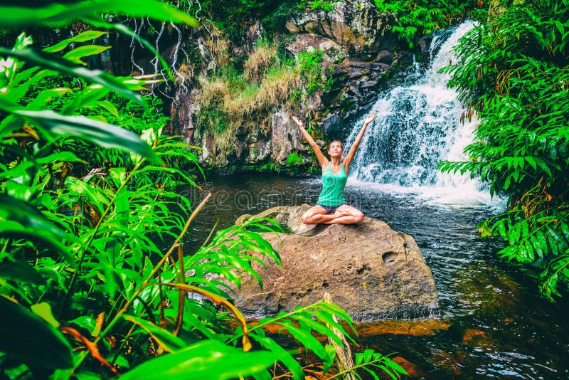 Yoga nature wellness meditation retreat woman at tropical waterfall forest in Kauai, Hawaii. Happy girl with open arms. In serenity enjoying lush outdoors