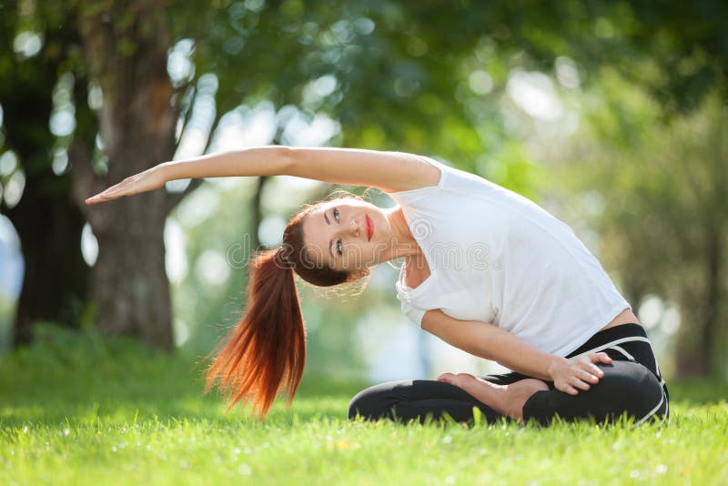 Yoga openlucht De gelukkige vrouw die yogaoefeningen doen, mediteert in het park Yogameditatie in aard Concept Gezonde levensstij stock fotografie Yoga openlucht De gelukkige vrouw die yogaoefeningen doen, mediteert in het park Yogameditatie in aard Concept Gezonde levensstij stock fotografie