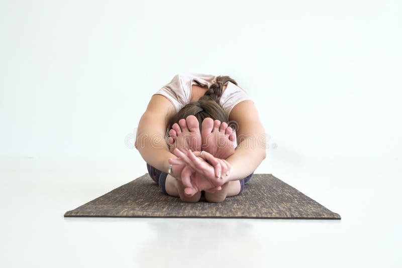 Yoga practicante de la muchacha, actitud delantera asentada de la curva, haciendo ejercicio del paschimottanasana fotos de archivo Yoga practicante de la muchacha, actitud delantera asentada de la curva, haciendo ejercicio del paschimottanasana fotos de archivo