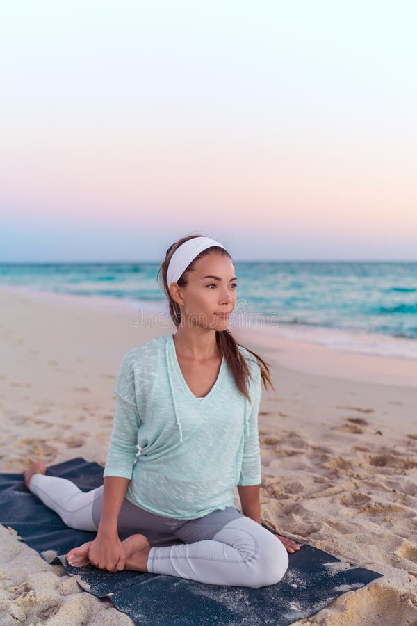 Yoga woman stretching legs doing pigeon pose leg stretch on beach at morning sunrise. Fitness healthy lifestyle stock photos Yoga woman stretching legs doing pigeon pose leg stretch on beach at morning sunrise. Fitness healthy lifestyle stock photos