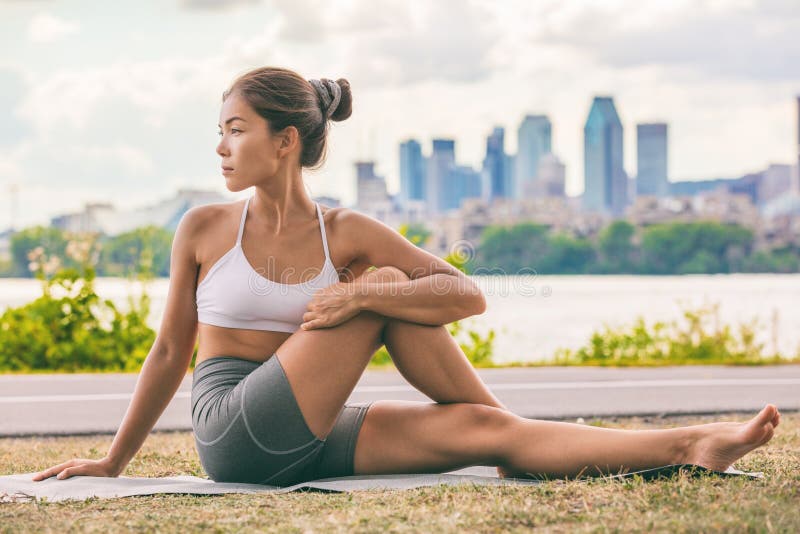 Yogaelasticitetsövningen passade den asiatiska kvinnan som sträcker lägre baksida för inbindningshälsa på stad som utomhus- kondi