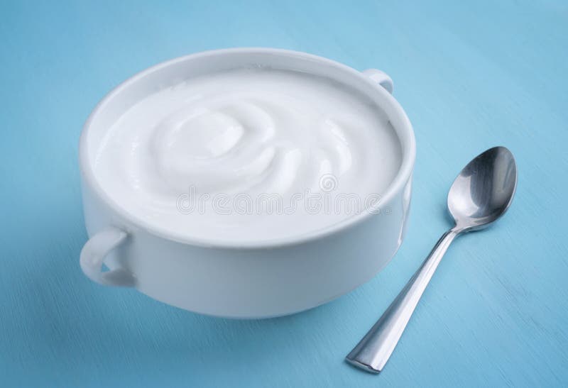 Yoghurt i en vit bunke med en sked fotografering för bildbyråer Yoghurt i en vit bunke med en sked fotografering för bildbyråer