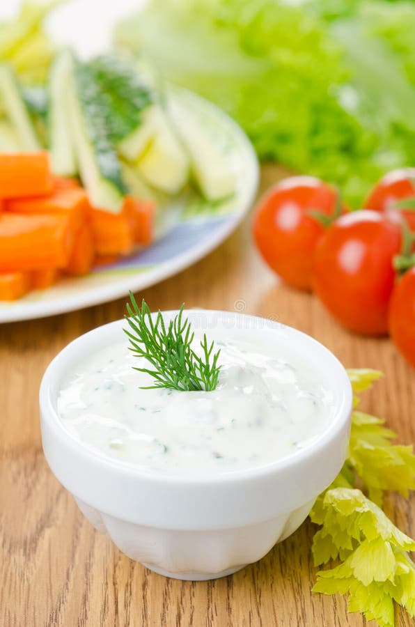 Yoghurt sauce with herbs to assorted fresh vegetables close-up