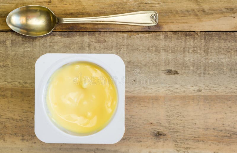 Yoghurtkopp på den lantliga trätabellen med den lilla skeden royaltyfria bilder Yoghurtkopp på den lantliga trätabellen med den lilla skeden royaltyfria bilder