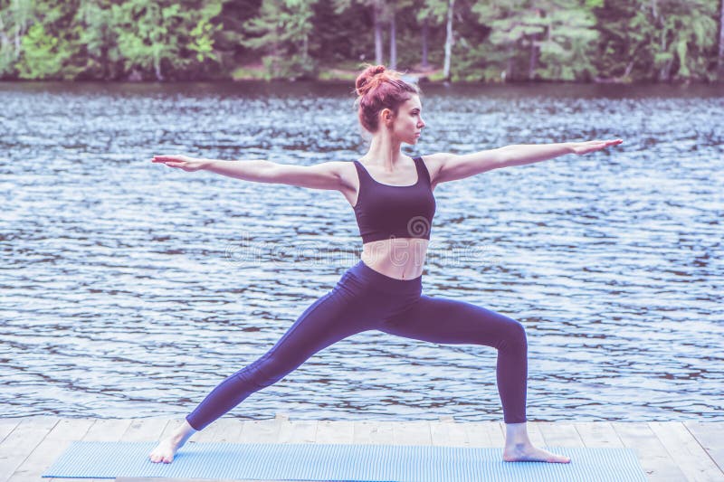 Yogi-flicka som utövar yoga, står i Warrior 2-träning, Virabhadrasana II-attityd på sjön Begreppet hälsosamt liv royaltyfri bild Yogi-flicka som utövar yoga, står i Warrior 2-träning, Virabhadrasana II-attityd på sjön Begreppet hälsosamt liv royaltyfri bild