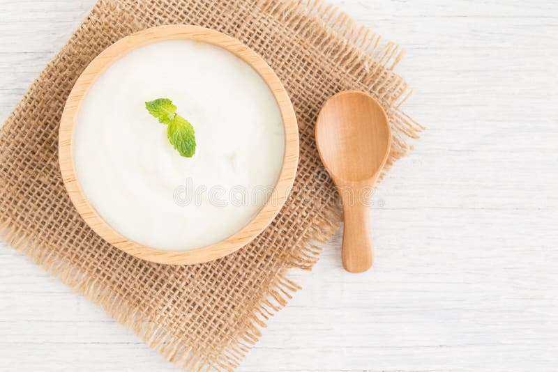 Yogur en el cuenco de madera en concepto sano de la comida de la tabla de madera blanca, la visión superior y el espacio de la co imagenes de archivo Yogur en el cuenco de madera en concepto sano de la comida de la tabla de madera blanca, la visión superior y el espacio de la co imagenes de archivo