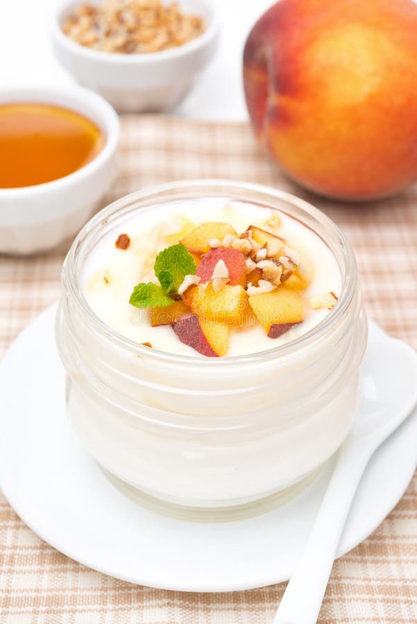 Yogur hecho en casa con la miel, los melocotones y las nueces, verticales imagen de archivo Yogur hecho en casa con la miel, los melocotones y las nueces, verticales imagen de archivo