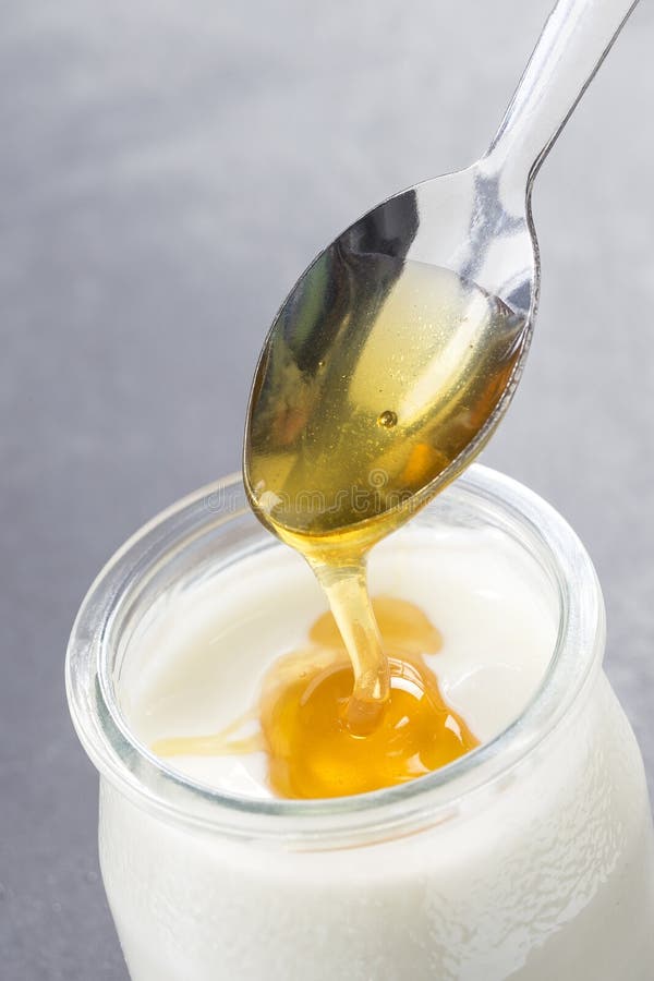 Yogurt and pouring honey on white background