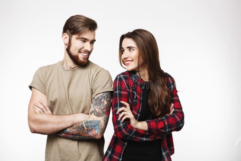 Yong tattooed man and nice woman standing crossing their hands.