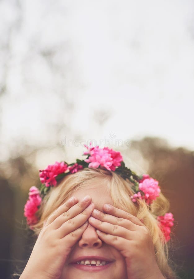 You cant see me. a cheerful little girl with her hands on her eyes playing hide and seek outside in nature.