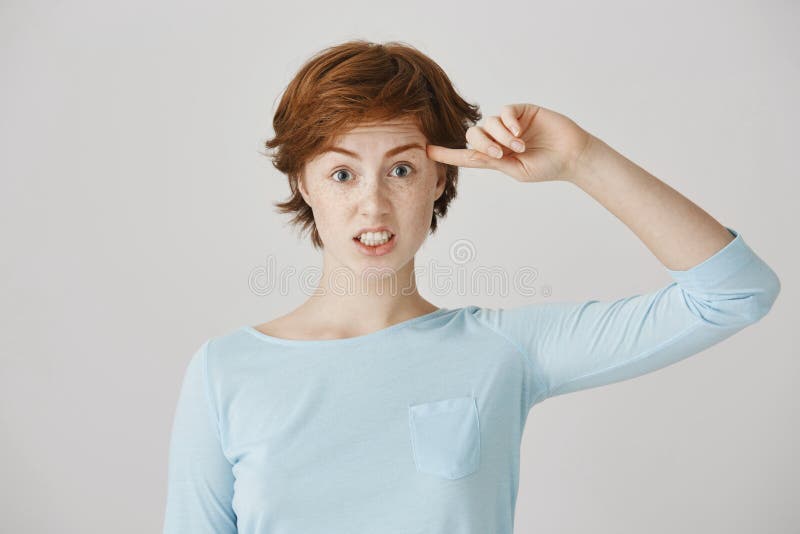 Are you insane or crazy. Portrait of irritated angry woman with ginger hair and freckles rolling index finger near royalty free stock photos Are you insane or crazy. Portrait of irritated angry woman with ginger hair and freckles rolling index finger near royalty free stock photos