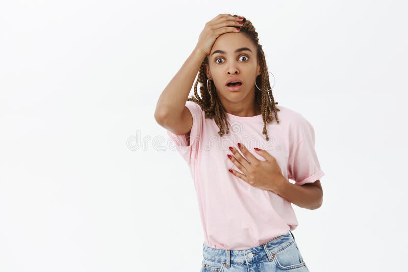 You scared me to death. Portrait of shocked speechless cute dark-skinned young female holding hand on dreads and heart royalty free stock image You scared me to death. Portrait of shocked speechless cute dark-skinned young female holding hand on dreads and heart royalty free stock image