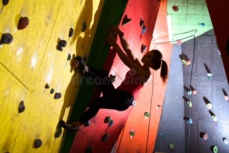 Young Active Woman Bouldering on Colorful Artificial Rock in Climbing Gym. Extreme Sport and Indoor Climbing Concept