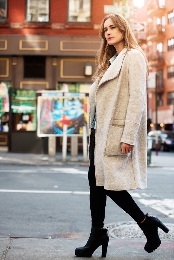 Young adul beautiful woman walking on city street wearing casual street style autumn outfit with grey jacket royalty free stock photography Young adul beautiful woman walking on city street wearing casual street style autumn outfit with grey jacket royalty free stock photography