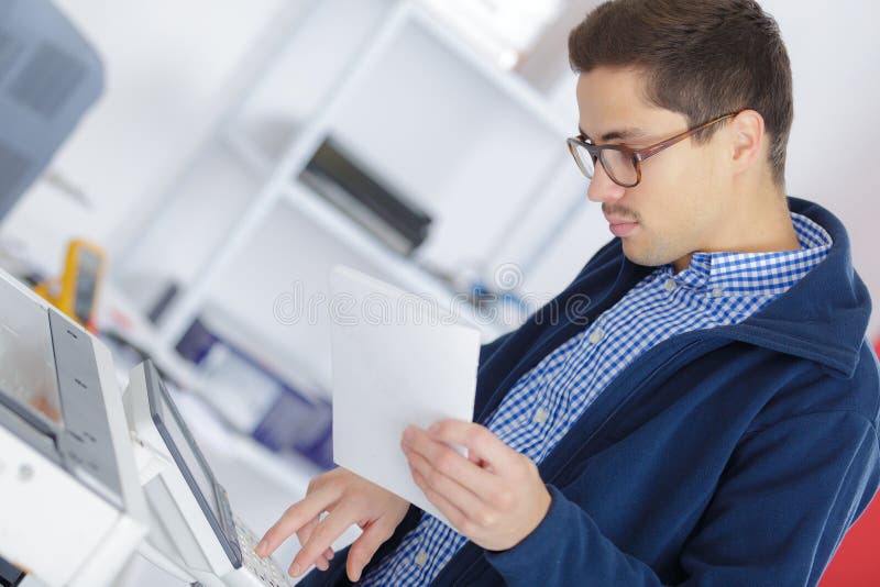 Young adult businessman using photocopy machine in office stock photo Young adult businessman using photocopy machine in office stock photo