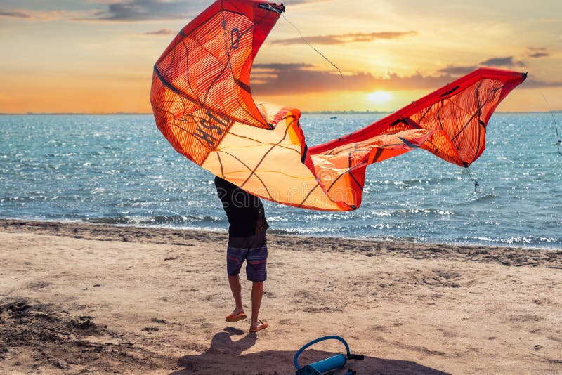 Young adult caucasian fit male person enjoy prepare kite surf board in sun uv protection suit on bright sunny day