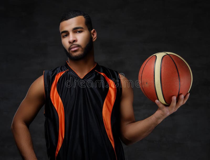 Young African-American basketball player in sportswear isolated over dark background.