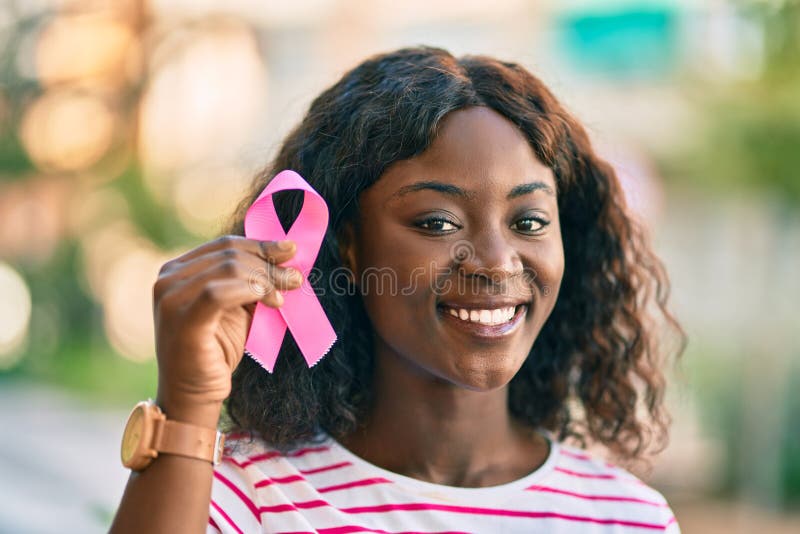 Young african american girl smiling happy holding pink breast cancer ribbon at the city royalty free stock photos