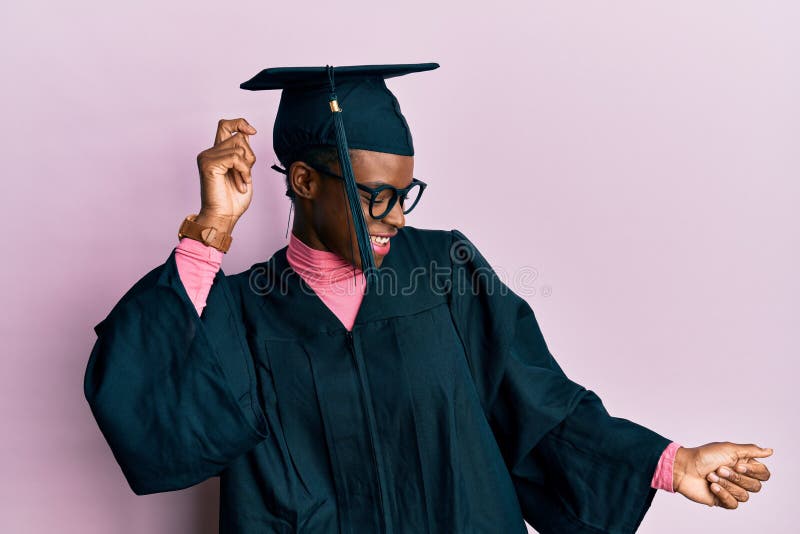 Young african american girl wearing graduation cap and ceremony robe dancing happy and cheerful, smiling moving casual and