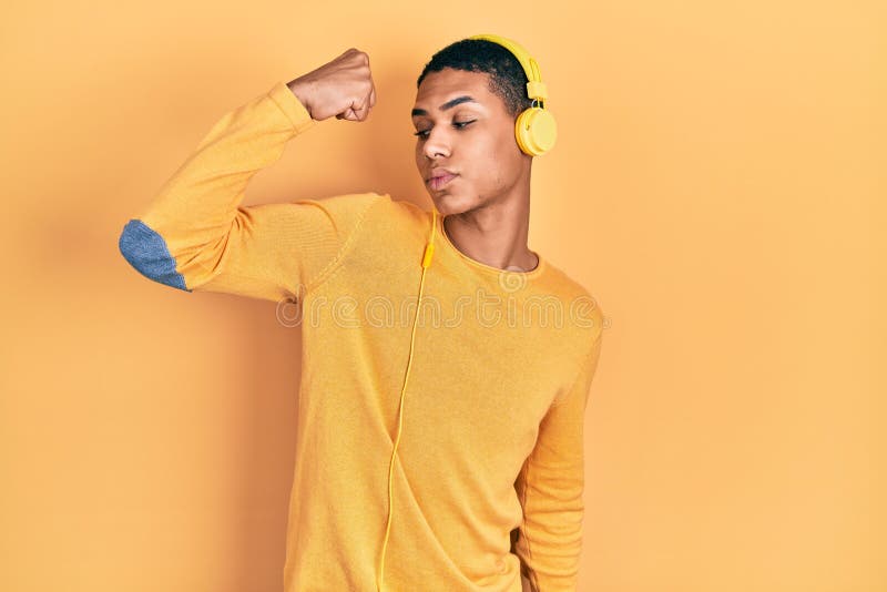 Young african american guy listening to music using headphones strong person showing arm muscle, confident and proud of power royalty free stock image