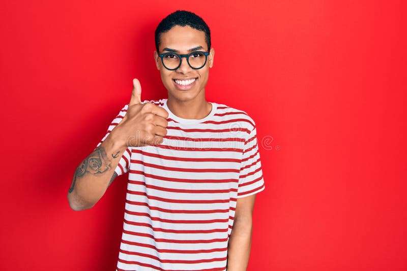 Young african american guy wearing casual clothes and glasses smiling happy and positive, thumb up doing excellent and approval royalty free stock photos