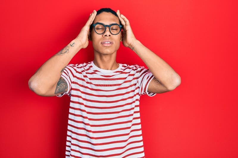 Young african american guy wearing casual clothes and glasses suffering from headache desperate and stressed because pain and stock photography