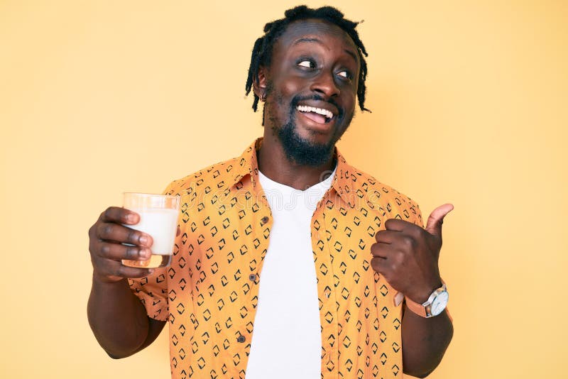 young-african-american-man-braids-holding-glass-milk-pointing-thumb-up-to-side-smiling-happy-open-mouth-219609837.jpg