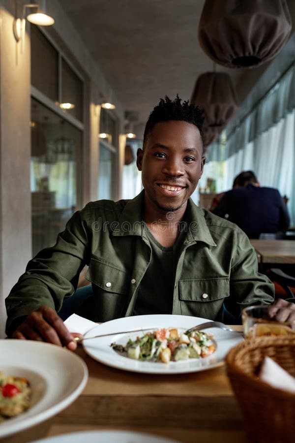 Young African American Man is Eating in a Restaurant Stock Image ...